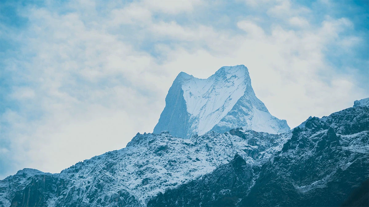 Annapurna peak towering over the landscape, with snow-capped summit and surrounding clouds.