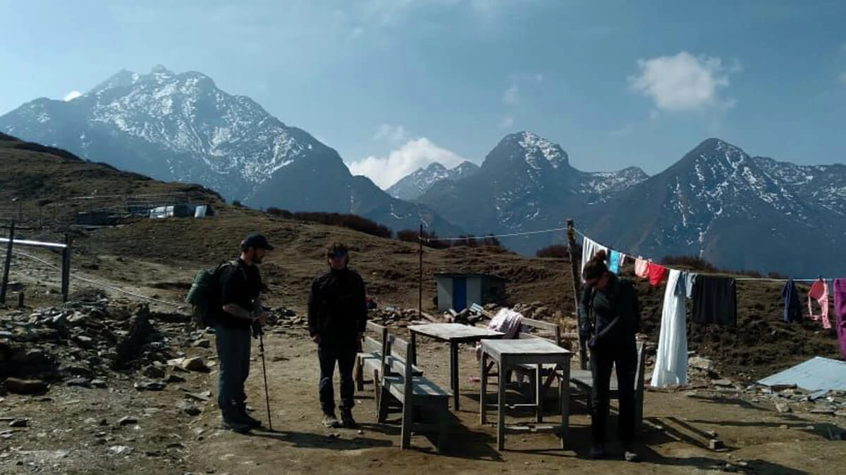 Trekkers standing outside a teahouse in Langtang Valley, surrounded by a vast sanctuary on a clear day.