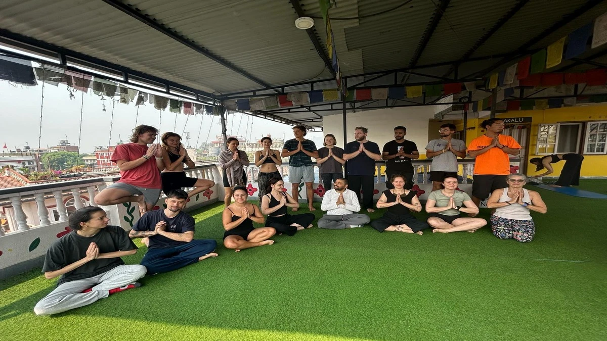 Trekking group and yoga guru practicing the Namaskar pose in a serene Yoga House during the Mardi Himal Yoga Trek, showcasing peaceful spiritual energy.