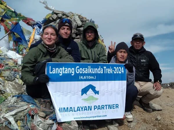 Group of happy trekkers posing together after completing the Langtang Valley Trek in Nepal, with scenic mountains covered with clouds.